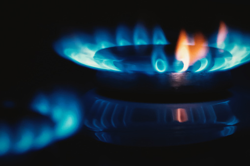 Gas flame, stove top cooker blue orange fire in the dark, copy space