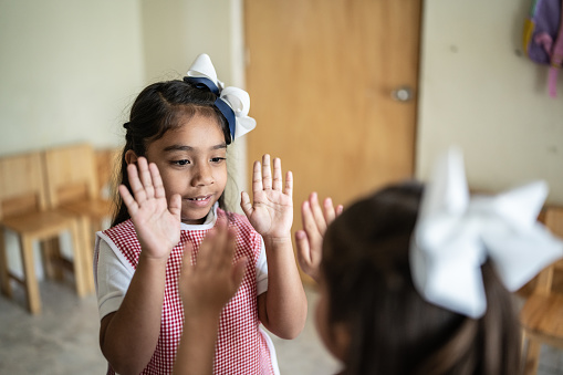 Girls playing hand game in the classroom at school