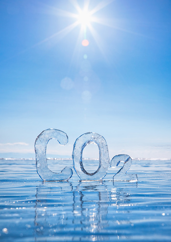 Chemical formula of greenhouse gas carbon dioxide CO2 made from ice on winter frozen lake Baikal under blue sky. Decarbonization concept.