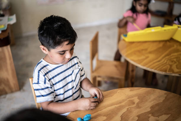 istock Boy playing with modeling clay in the classroom at school 1416117793