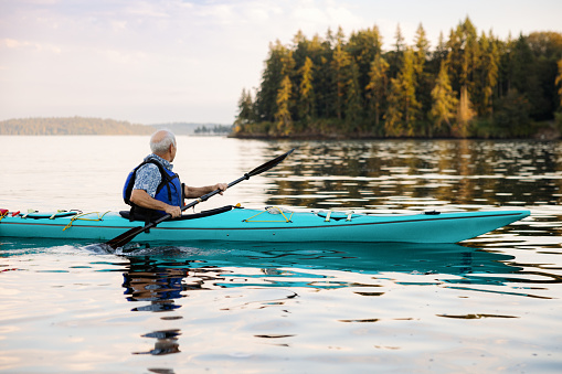 A Caucasian man in his late 70's enjoys an active lifestyle with his kayak.  Healthy living in the PNW on the Puget Sound in Washington state.