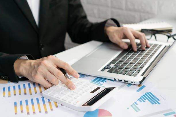 istock Businessman's hand using calculator calculate business report, marketing data, financial graph, spreadsheet while using computer on desk at office. Business analysis, investment and finance concept. 1416163175