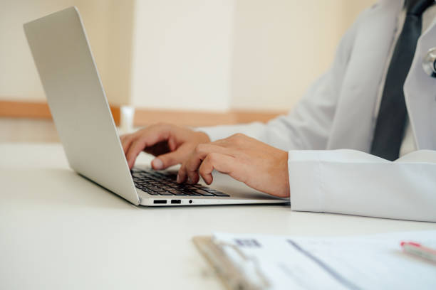 istock Doctor expert wearing white coat using laptop and reading clipboard report 1416165045