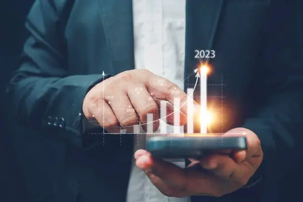Photo of Businessman using smartphone analyzes the profitability of working companies with digital augmented reality graphics, positive indicators in 2023, a business calculates financial data for investments.