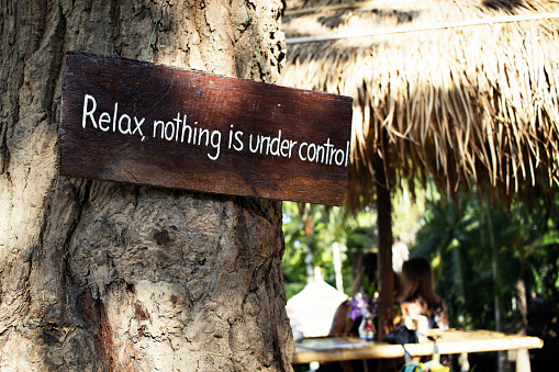 Wooden Sign that says Relax Nothing is Under Control. Vacation and Holiday conceptual image