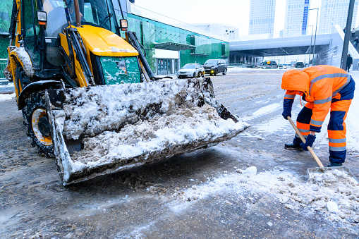 Moscow, Russia - January 18, 2022: Snow removal on city streets. Snowplow, snowdrifts in a snowfall.