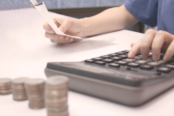 Women's hands hold  bill and using calculator with stack of coin , bank note and calculator, a money-saving concept and investment and account concept