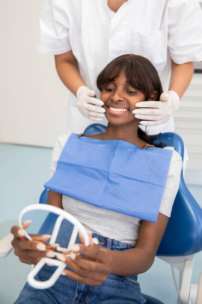 istock Smiling African American patient looking at her teeth in mirror 1416186117