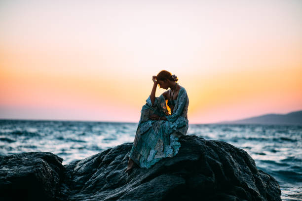 Sad Woman Sitting on the Cliffs on the Beach
