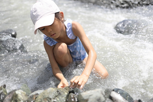 Japanese student girl damming river by stone (7 years old)