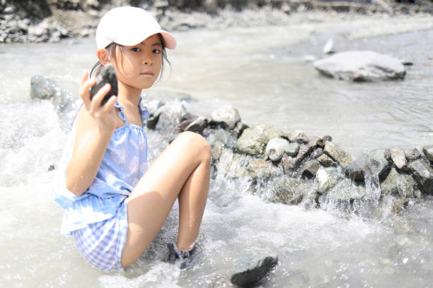 Japanese student girl damming river by stone (7 years old)