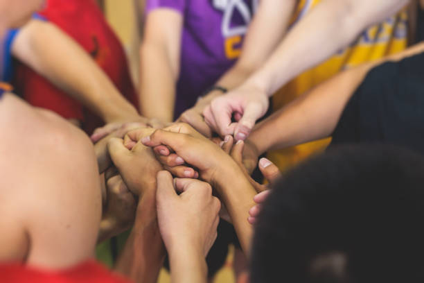 Team of kids children basketball players stacking hands in the court, sports team together holding hands getting ready for the game, playing indoor basketball, team talk with coach, close up of hands equipo de niños jugadores de baloncesto apilando las manos en la cancha, equipo deportivo juntos tomándose de la mano preparándose para el juego, jugando baloncesto en interiores, charla de equipo con el entrenador, primer plano de manos