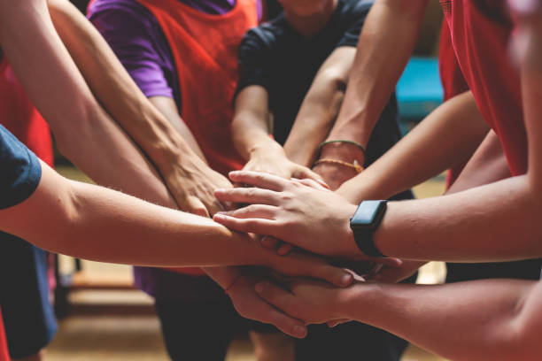 Team of kids children basketball players stacking hands in the court, sports team together holding hands getting ready for the game, playing indoor basketball, team talk with coach, close up of hands stock photo