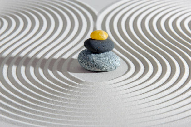 Japanese zen garden with yin yang stone in textured sand stock photo