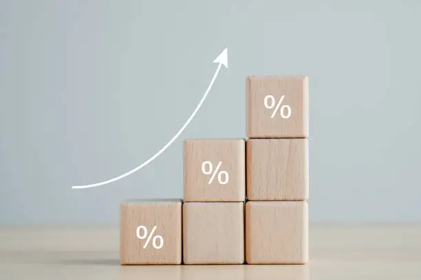 Photo of Interest rate finance and mortgage rates concept. Wooden blocks with percentage sign and rise of arrow up, financial growth, interest rate increase, inflation, sale price and tax rise concept.