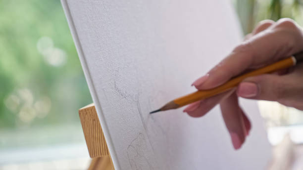 istock Person hands draw flowers using pensil on easel closeup 1416254917