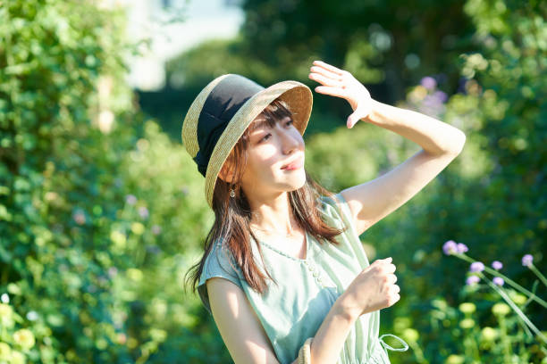 una mujer bloqueando la fuerte luz del sol con la mano - luz ultra violeta fotografías e imágenes de stock