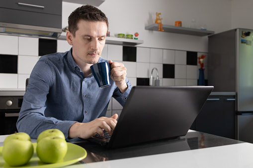 Man drinking coffee while taking break from work in home office.