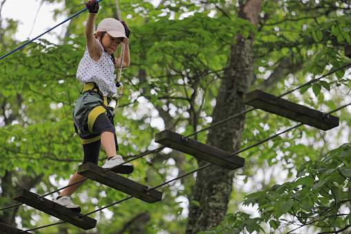 Japanese student girl playing at outdoor obstacle course on tree (7 years old)