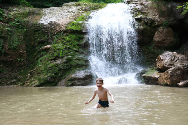 istock Kid bathing in Rufabgo stream next to waterfall Shum 1416286815
