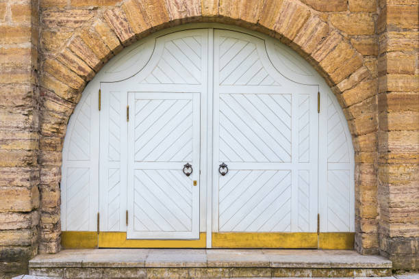 A large antique double-leaf wooden door under a semicircular stone arch. Vintage style of construction.