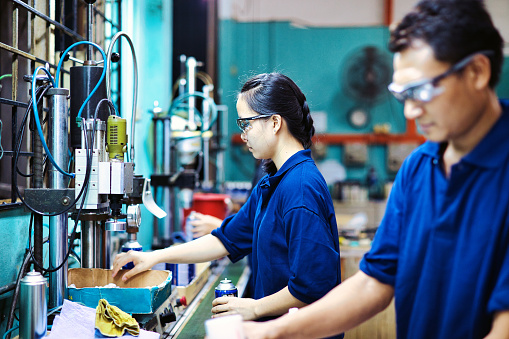 Asian woman alongside man working as a team in a factory lab