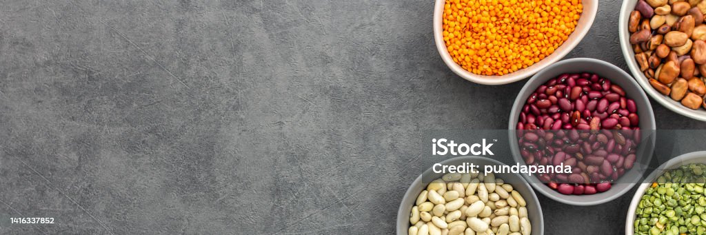 Different types of legumes in bowls Banner of different types of legumes in bowls, yellow and green peas and lentils, colored beans and maash, top view, copy space Bean Stock Photo