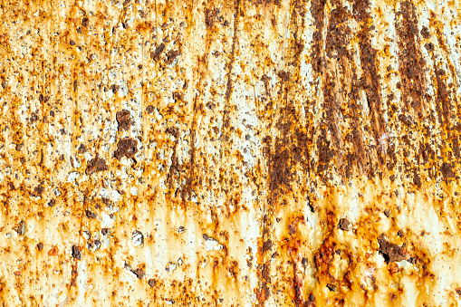 Rusty metal wall with cracked white paint.