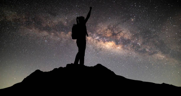 milky way. night sky with stars and silhouette of a standing mountaineer man with yellow light on the mountain. space background - milky way galaxy space star imagens e fotografias de stock