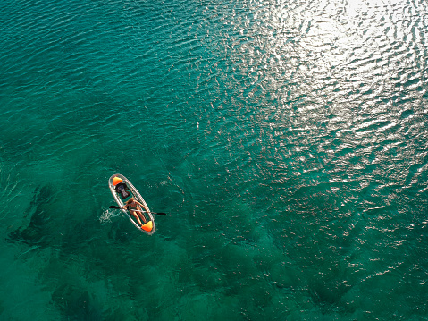 Woman paddling crystal kayak from above