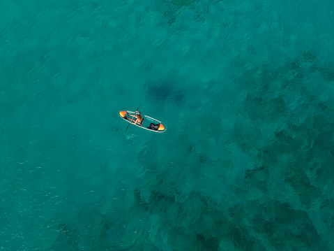 Woman paddling crystal kayak from above