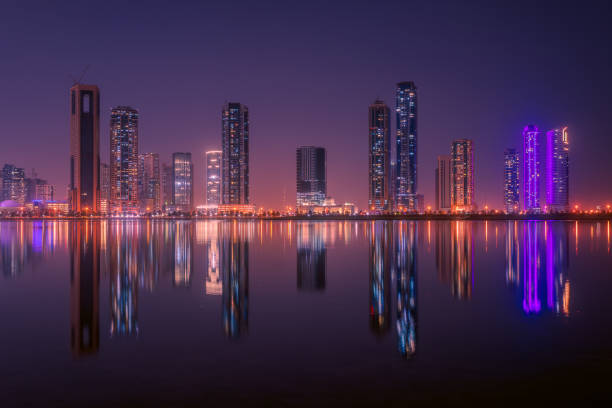 View of skyscrapers in Sharjah at night, United Arab Emirates Sharjah is a city and emirate in the United Arab Emirates, famous for its luxurious shopping and modern architecture, in which skyscrapers are scattered, and its bright lights reflecting on the water. sharjah city stock pictures, royalty-free photos & images