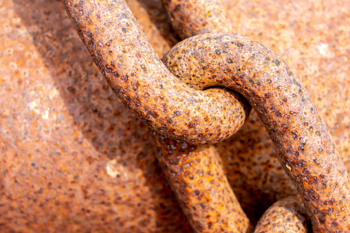 Extreme close-up of a rusty chain on a rusty tube on a shipyard. With copy space. Shot with a 35-mm full-frame 61MP Sony A7R IV.