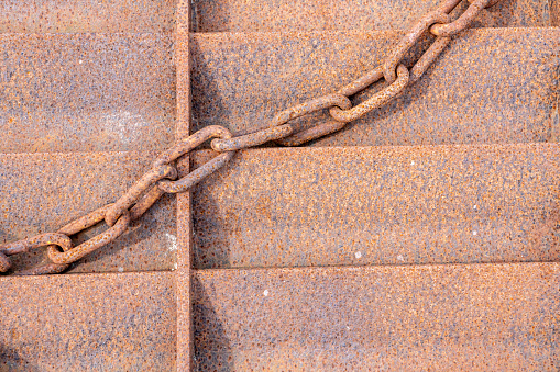 Close-up of a rusty chain on metal plating. With copy space. Shot with a 35-mm full-frame 61MP Sony A7R IV.