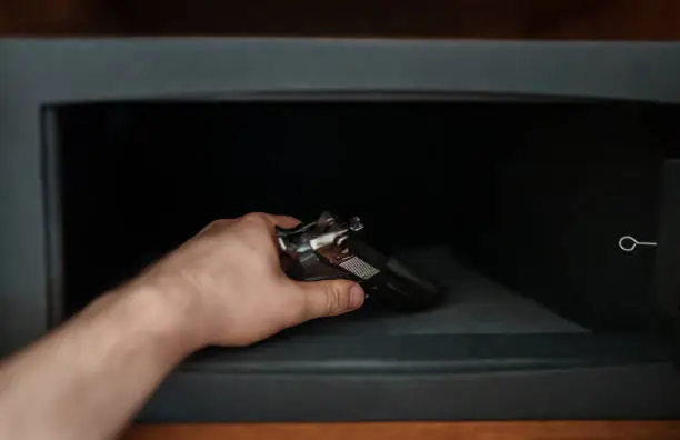 Photo of Man puts the weapon in the safe.