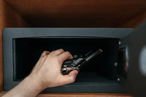 Photo of Man puts the weapon in the safe.