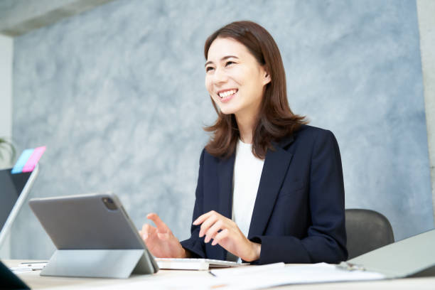 mulher de negócios fazendo trabalho de mesa com um sorriso - japonês - fotografias e filmes do acervo