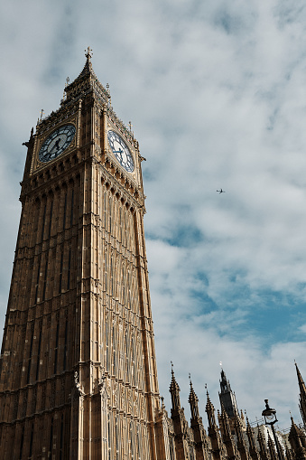 Photograph of Big Ben with a plane flying close by. Colour graded with slight film grain.
