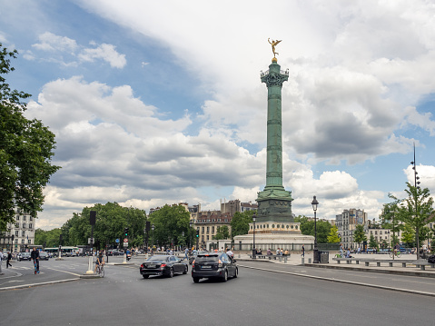 View across Boulevard Henri-IV and a pedestrian crossing to the Place de la Bastille and the Column of July monument under a partly cloudy sky. 06/04/2022 - Pl. de la Bastille, 75004 Paris, 11th arrondissement, France