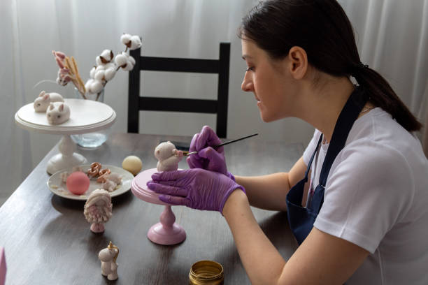 istock Woman decorates chocolate bear figurine with brush. Selective focus. Image for articles about confectionery. 1416413794