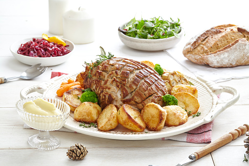 Baked meat and potatoes, with salad and mayo as a special occasion lunch served on a wooden table.