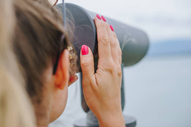 Young female using public binoculars. Female looks through stationary binoculars. Binoscope on observatrion post near Zadar.
