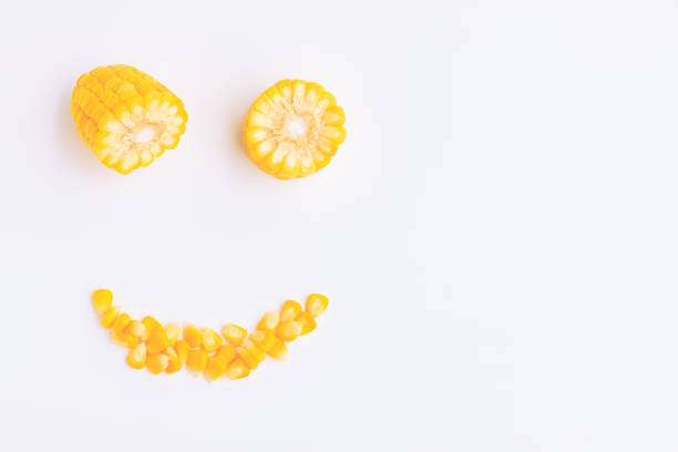 Yellow corn cobs slice and seeds on pink background, Smile face