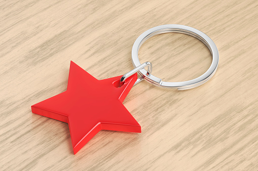 Keyring with shiny red star on wood background