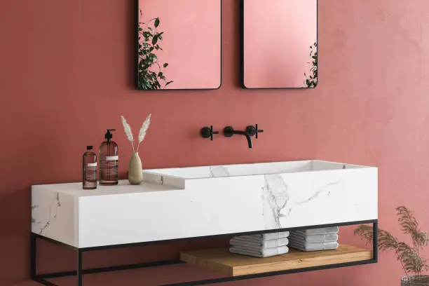 Close up of white marble basin with two mirrors hanging in on red wall, minimal cabinet with black faucet in minimalist bathroom. Front view. 3d rendering