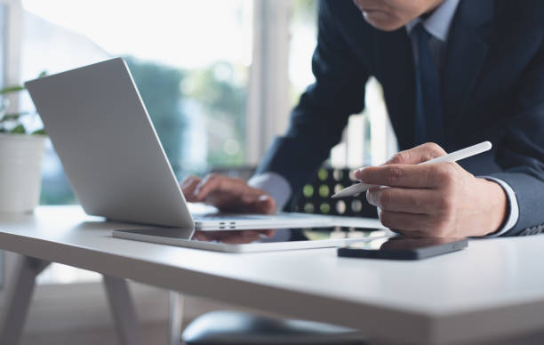istock Asian businessman working on laptop computer, surfing the internet with digital tablet and mobile smart phone on office table 1416425154