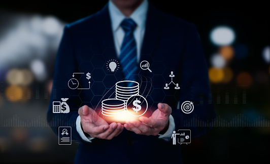 A businessman holding a coin represents an analytical business notion such as the stock market, currency exchange, or banking, with a growing virtual hologram of data, graphs, and charts.