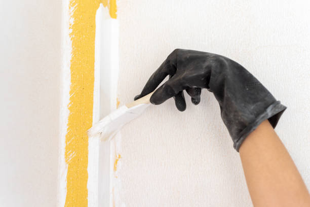 istock Concept of home improvement and renovation. Applying white paint using a paintbrush and wearing rubber gloves. 1416428311