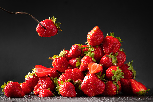 A hill of red Strawberry with water drops on a dark background close-up. Useful dietary product.