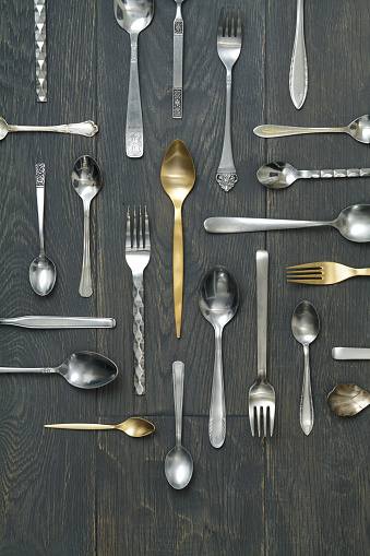 Variety of spoons and forks on a rustic wooden table, top view with a copy space